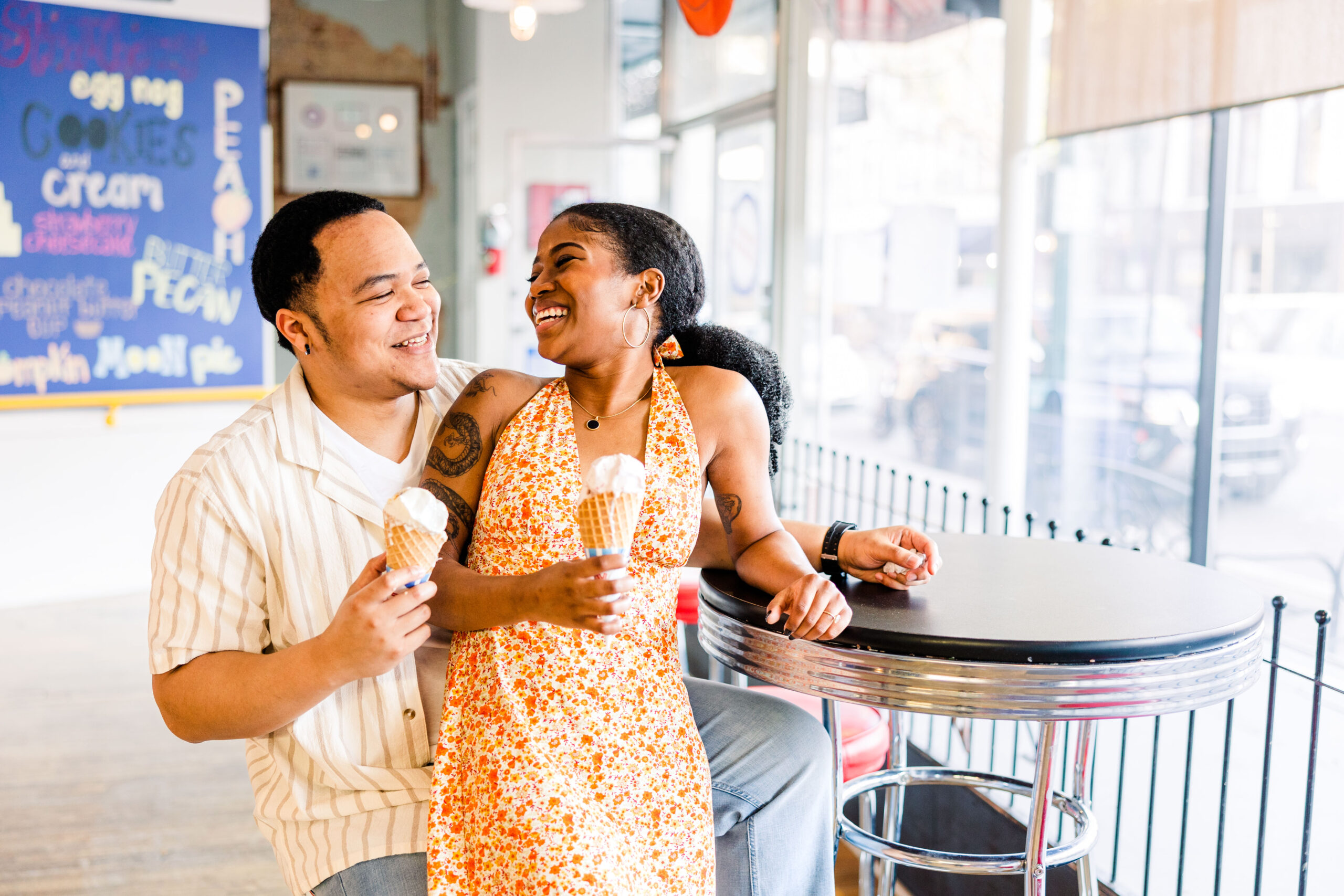 Couple flirting and laughing while enjoying ice cream during their engagement session