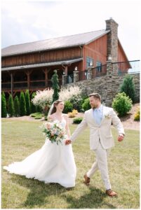 Bride and groom walking hand-in-hand outdoors, smiling at each other.