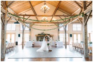 Bride and groom dancing in a beautifully decorated rustic barn.