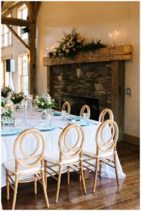 Elegant reception table setup with floral centerpieces in a rustic barn.