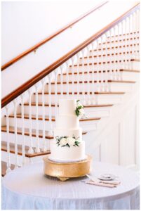 Wedding cake displayed on a table by the staircase.