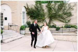 Bride and groom holding hands and smiling at Separk Mansion.