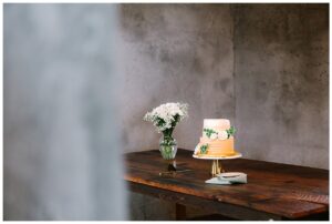 Close-up of a wedding cake on a wooden table with floral decorations in a rustic setting at Overlook Barn in Banner Elk, NC.