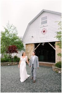 Bride and groom walking hand in hand outside the barn at Overlook Barn in Banner Elk, NC, with rustic wooden doors in the background.