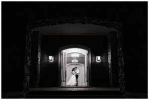 Bride and groom share a quiet moment in the doorway of Vanlandingham Estate, Charlotte, NC, captured in black and white.