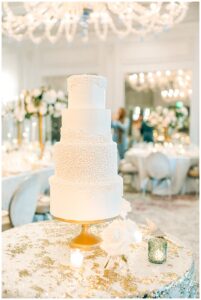 Elegant white wedding cake with intricate detailing on a decorated table.