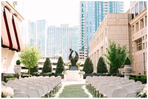 Outdoor wedding ceremony setup with city buildings in the background.